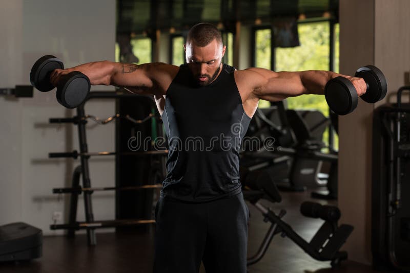 Muscled мужская модель работая плеча с гантелями стоковые изображения Muscled мужская модель работая плеча с гантелями стоковые изображения