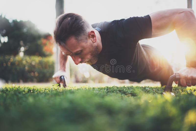 Muscolare atleta esercizio push up esterno in parco soleggiato.