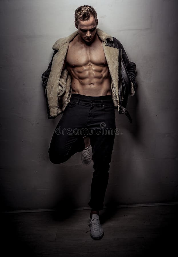 Muscular athlete young man posing over light gray wall