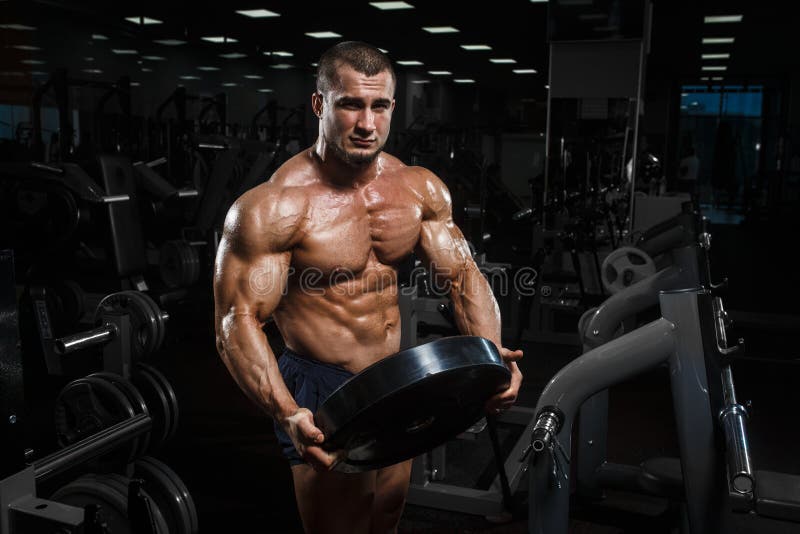 Muscular athletic bodybuilder fitness model posing after exercises