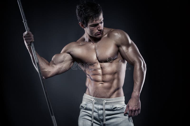 Muscular bodybuilder guy doing posing with dumbbells over black background