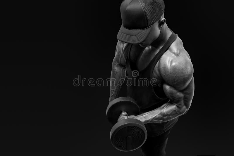 Black and white shot of muscular bodybuilder wearing a tank top and black cap doing biceps curl with dumbbell against black background.