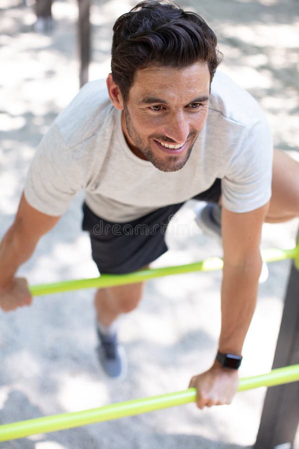 Muscular Build Man Doing Pull Ups Exercises on Horizontal Bars Stock