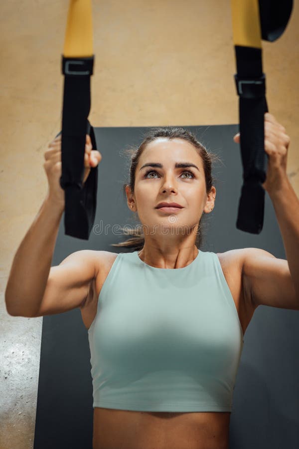 Muscular Fit Woman Doing Pull Up Exercise Using Suspension Trainer