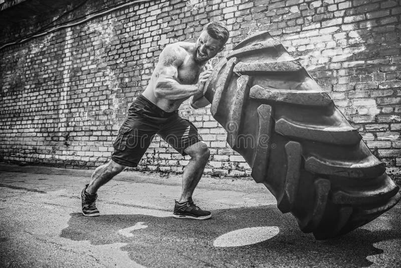 Muscular fitness shirtless man moving large tire. stock photo Muscular fitness shirtless man moving large tire. stock photo