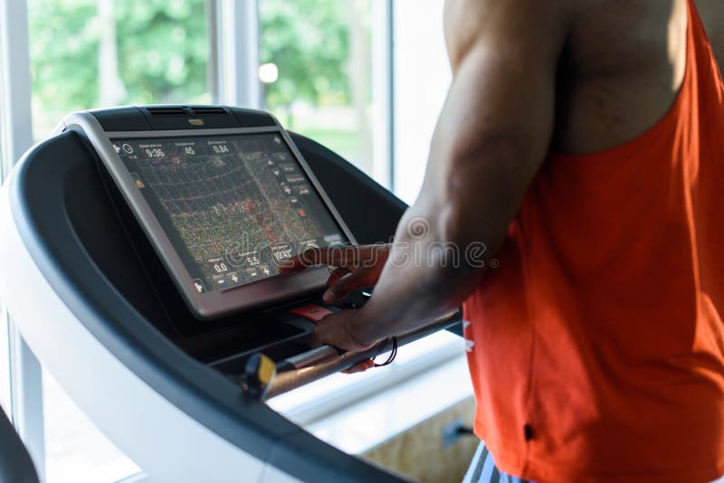 Muscular handsome black man jogging on a treadmill in the gym stock images