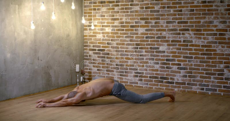 A Muscular, Lithe, Bearded Man is Doing Yoga in a Gym Against a Brick ...