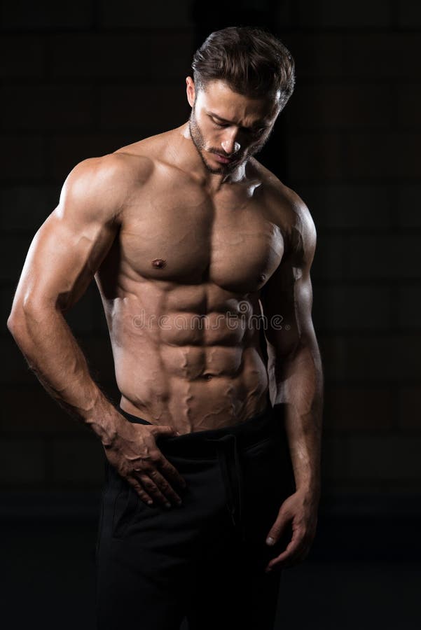 Handsome Man Standing Strong In The Gym And Flexing Muscles - Muscular Athletic Bodybuilder Fitness Model Posing After Exercises. Handsome Man Standing Strong In The Gym And Flexing Muscles - Muscular Athletic Bodybuilder Fitness Model Posing After Exercises