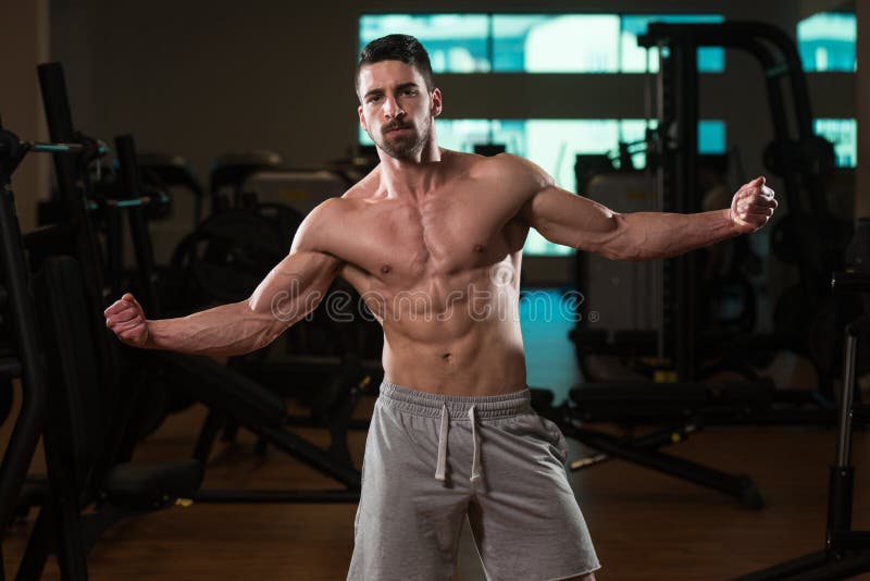 Muscular Man Flexing Muscles In Gym