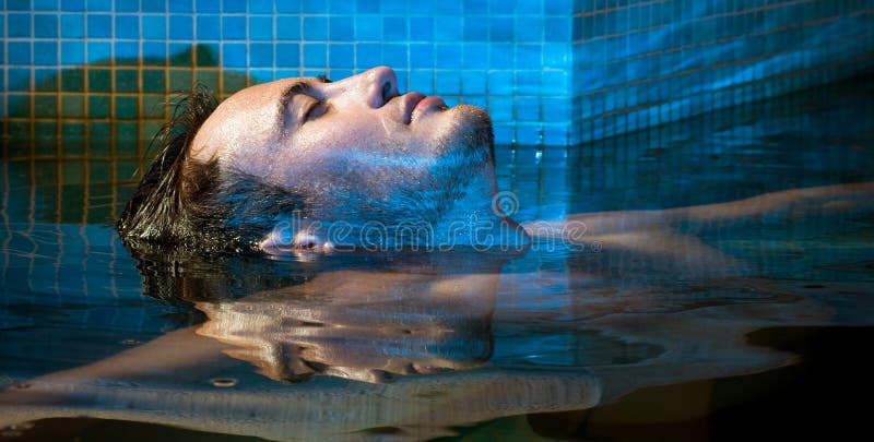 Muscular man posing in the swimming pool