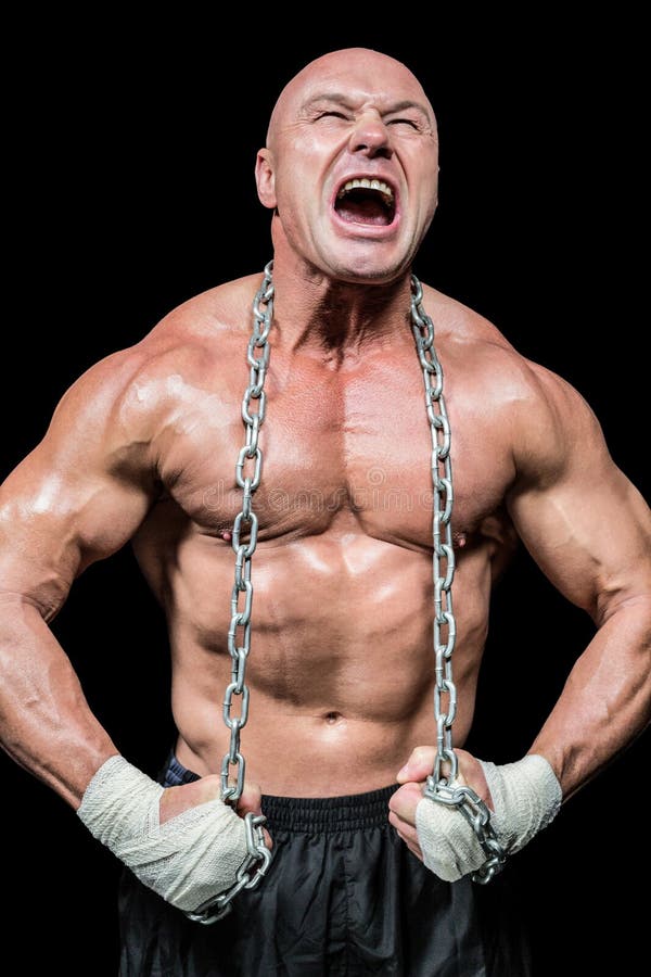 Muscular man shouting while flexing muscle against black background