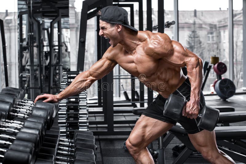 Muscular man working out in gym doing exercises for back. Single Arm Dumbbell Row