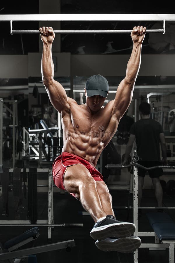 Muscular man working out in gym, doing stomach exercises on a horizontal bar, strong male naked torso abs royalty free stock photography Muscular man working out in gym, doing stomach exercises on a horizontal bar, strong male naked torso abs royalty free stock photography