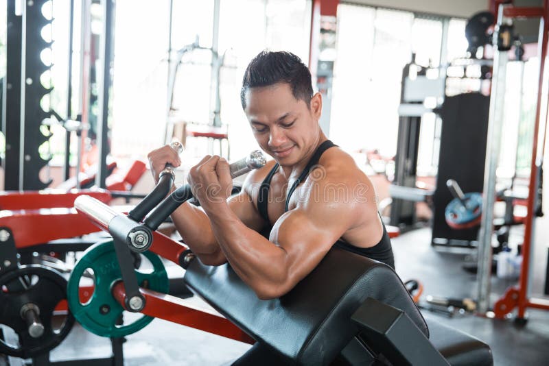 Muscular man workout on exercise machine stock photo Muscular man workout on exercise machine stock photo