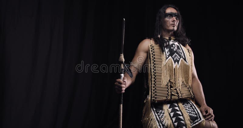 Muscular native american man in traditional costume is holding a spear, 4k