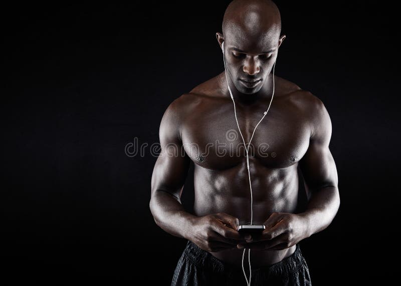 Muscular young man listening music on mobile phone