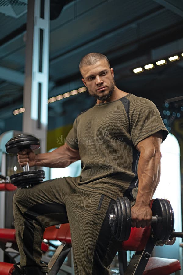 Musculär manlig idrottsutbildning med dumbbell på ett modernt gym under en träningssession arkivbilder