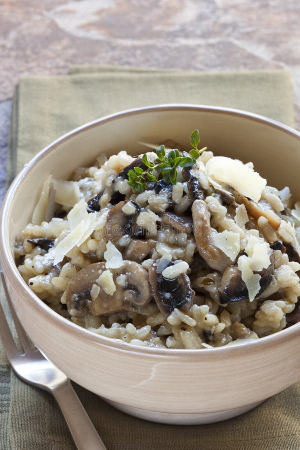 Bowl of mushroom risotto, garnished with thyme and parmesan.