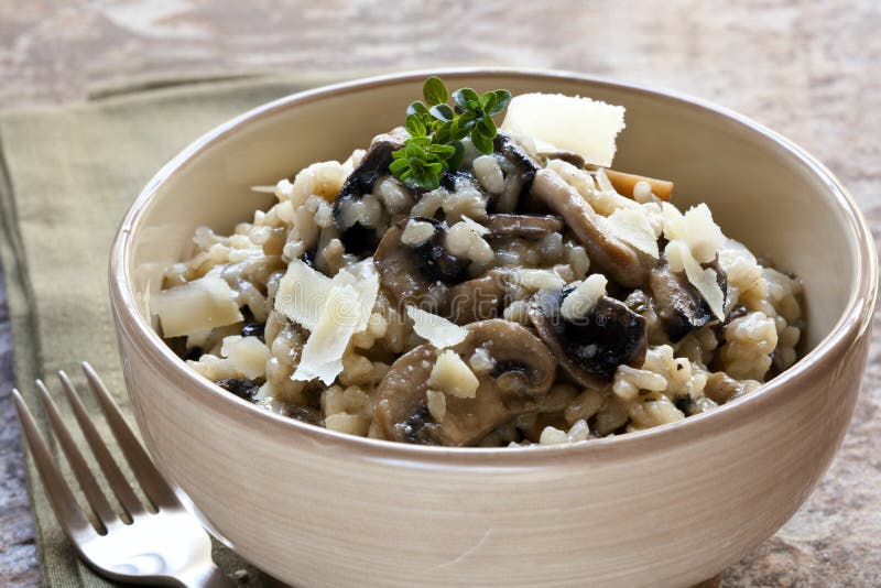 Bowl of mushroom risotto, garnished with thyme and parmesan.