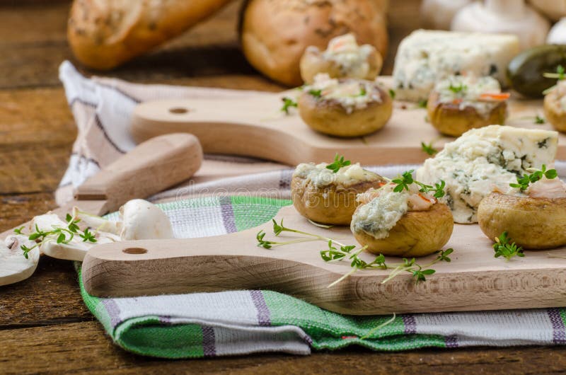 Mushrooms stuffed with cheese. Mushrooms stuffed with blue cheese, microgreens on top, simple delicious food snack stock photos