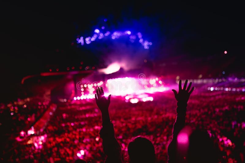 Music concert with lights and silhouette of a woman enjoying the concert. Girl hands at concert, loving the artist and the festiv