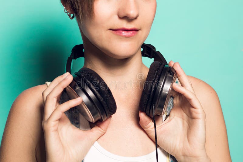 Music headphones on a girl`s neck.Woman with music helmets. 