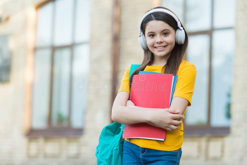 Music lesson. Little child hold books for private lesson. School lesson. Engish learner wear headphones. Listening