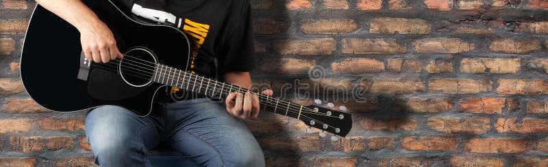 Fragment man play a black acoustic guitar on a old brick wall background stock image Fragment man play a black acoustic guitar on a old brick wall background stock image