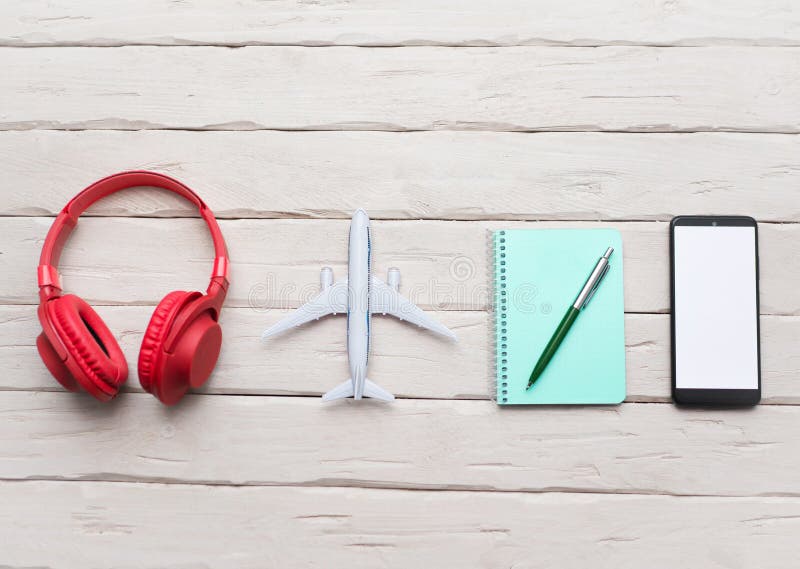 Musical headphones with a notepad, with a smartphone with a white display for a playlist. Headphones on the table with an airplane stock photo