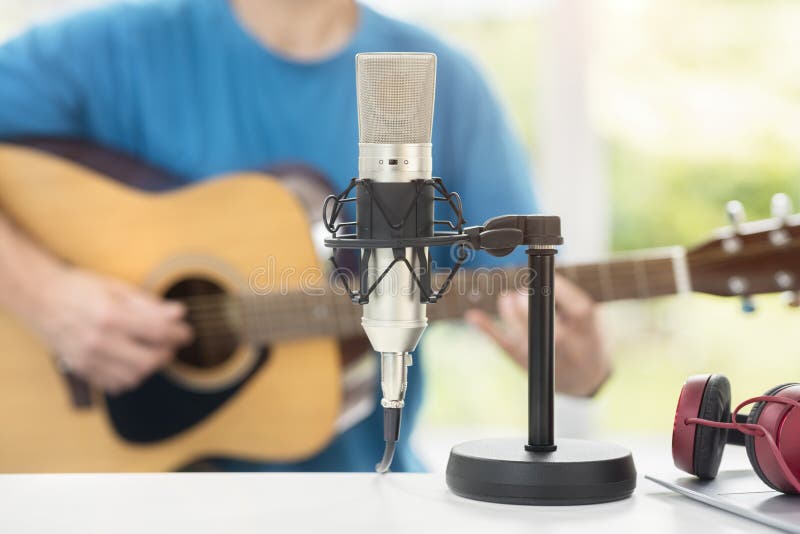 Musician with microphone playing acoustic guitar and recording music on computer. Or learning fom online lesson stock image Musician with microphone playing acoustic guitar and recording music on computer. Or learning fom online lesson stock image