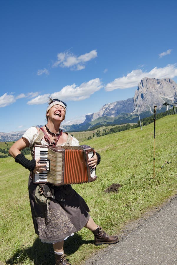 Yodelling musician with flowers in hair and garb in front of Dolomites, South Tyrol, Italy. Yodelling musician with flowers in hair and garb in front of Dolomites, South Tyrol, Italy