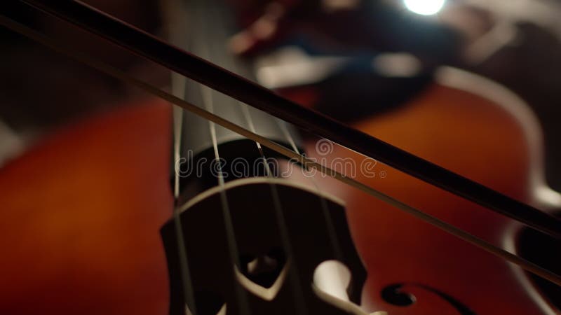 Musician plays classical music with bow on cello, closeup. Bow plays music on strings of musical instrument. Concept of stock video