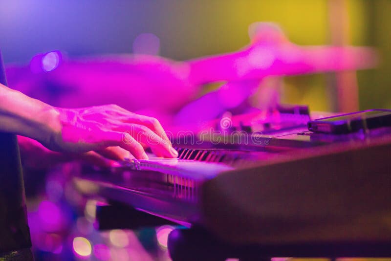 Musician`s hands playing keyboard at a live show on stage with blurry musical instrument stock photography Musician`s hands playing keyboard at a live show on stage with blurry musical instrument stock photography