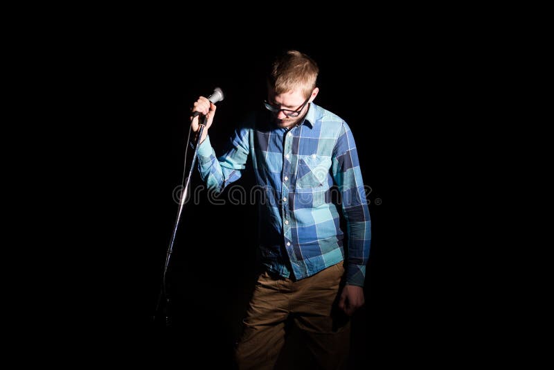 Musicien chantant au microphone sur un concert dans des contre-jours d'étape images libres de droits Musicien chantant au microphone sur un concert dans des contre-jours d'étape images libres de droits