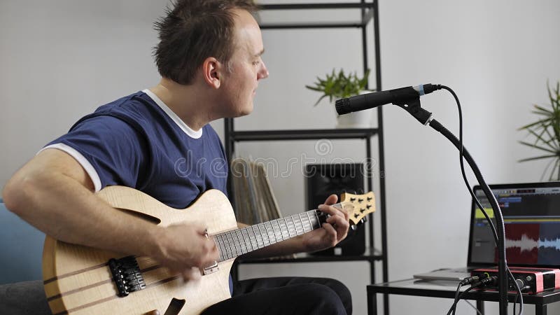 Musicien chantant et jouant la guitare électrique dans le studio à la maison de musique
