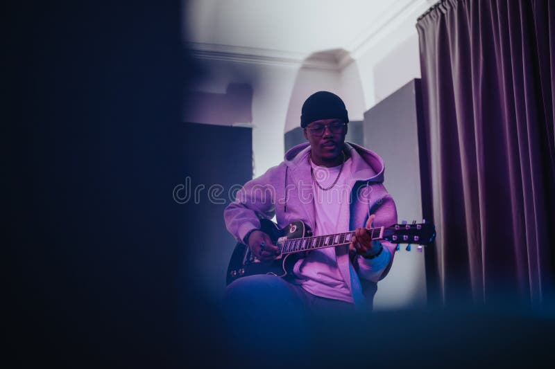 Musicien jouant de la guitare dans un environnement de studio créatif et dynamique photographie stock libre de droits