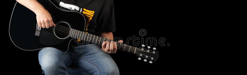 Musik - fragmentmanlek en svart svartbackgrou för akustisk gitarr. Musik - fragmentmanlek en svart akustisk gitarr på en svart bakgrund