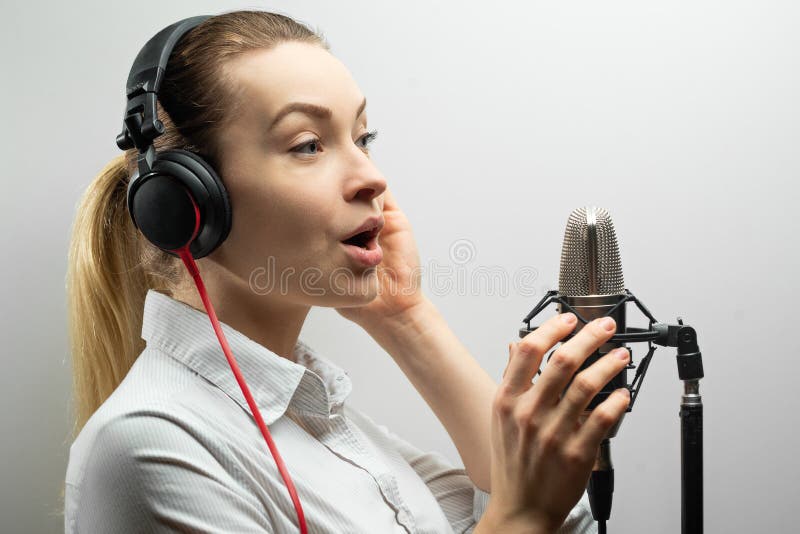 Musik, showbusiness, folk och stämmabegrepp - sångare med hörlurar och mikrofonen som sjunger en sång i inspelningstudio, royaltyfri bild Musik, showbusiness, folk och stämmabegrepp - sångare med hörlurar och mikrofonen som sjunger en sång i inspelningstudio, royaltyfri bild