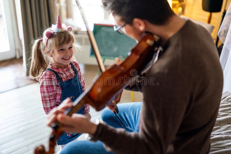 Musik är så kul. Ung far som undervisar sin lilla dotter att spela fiolin och le. royaltyfria foton