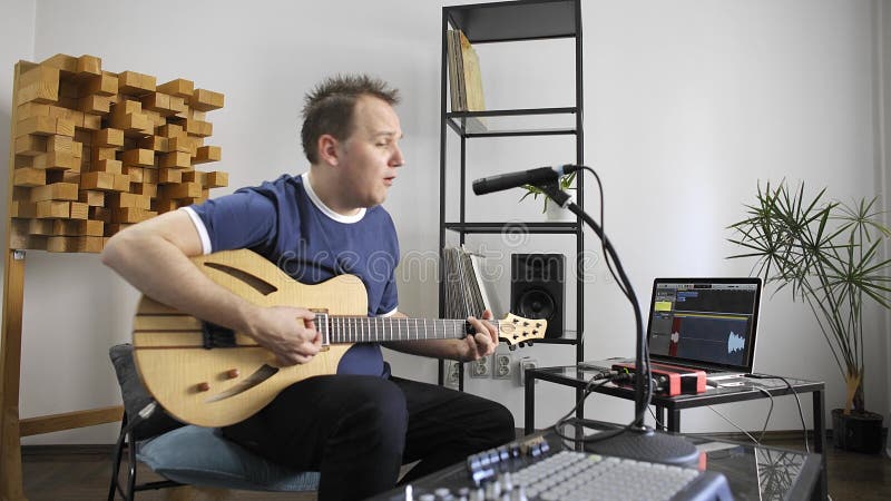 Musiker som sjunger och spelar den elektriska gitarren i hem- musikstudio