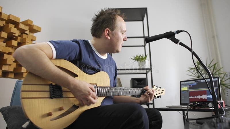 Musiker som sjunger och spelar den elektriska gitarren i hem- musikstudio