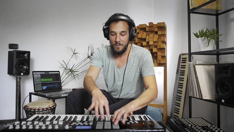Musiker som spelar det midi tangentbordet i hem- musikstudio