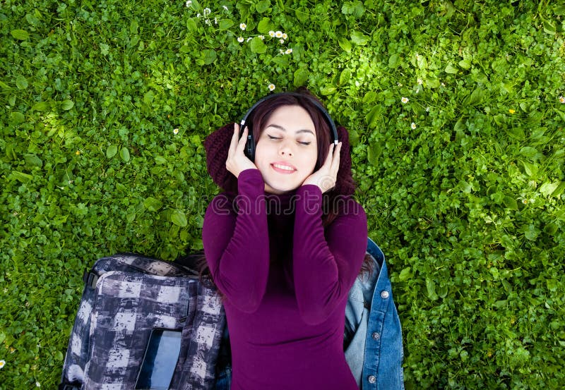 Musique de ?coute de jeune femme mignonne avec des ?couteurs photo stock Musique de ?coute de jeune femme mignonne avec des ?couteurs photo stock