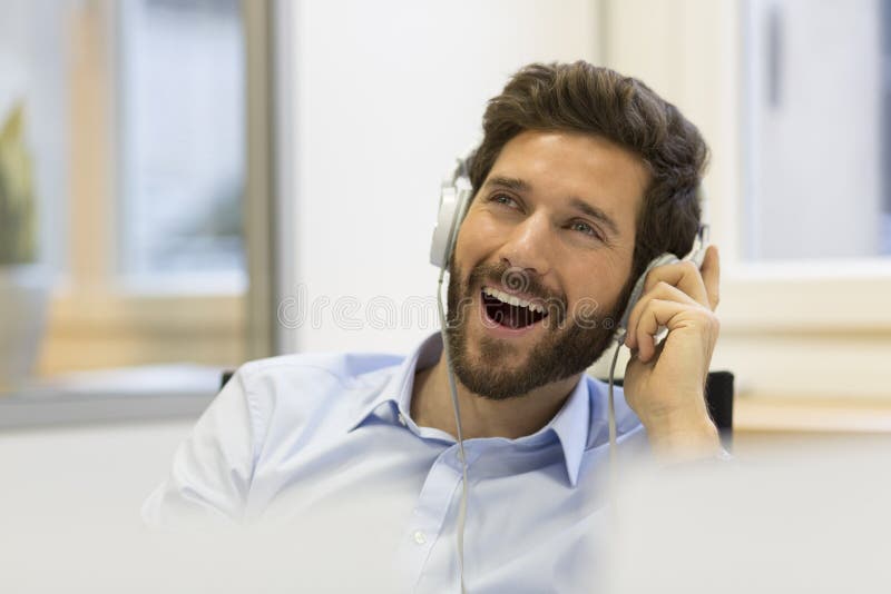 Musique de écoute d'homme d'affaires et chant dans le bureau moderne photographie stock libre de droits Musique de écoute d'homme d'affaires et chant dans le bureau moderne photographie stock libre de droits