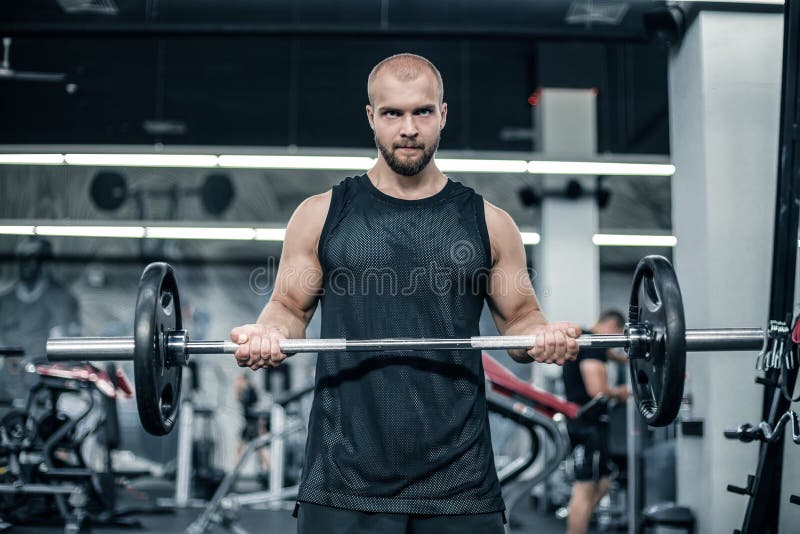 Muskul?s man som utarbetar i idrottshallen som g?r ?vningar med skivst?ngen p? biceps, stark man fotografering för bildbyråer Muskul?s man som utarbetar i idrottshallen som g?r ?vningar med skivst?ngen p? biceps, stark man fotografering för bildbyråer