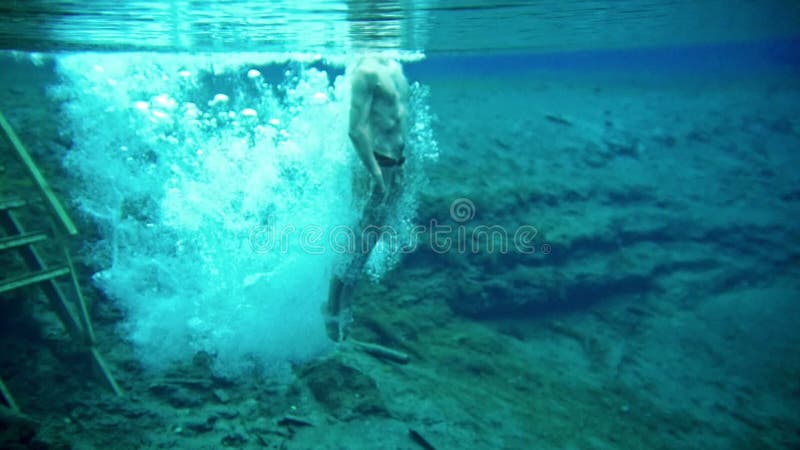 Muskulöser junger Mann taucht in den klaren blauen See