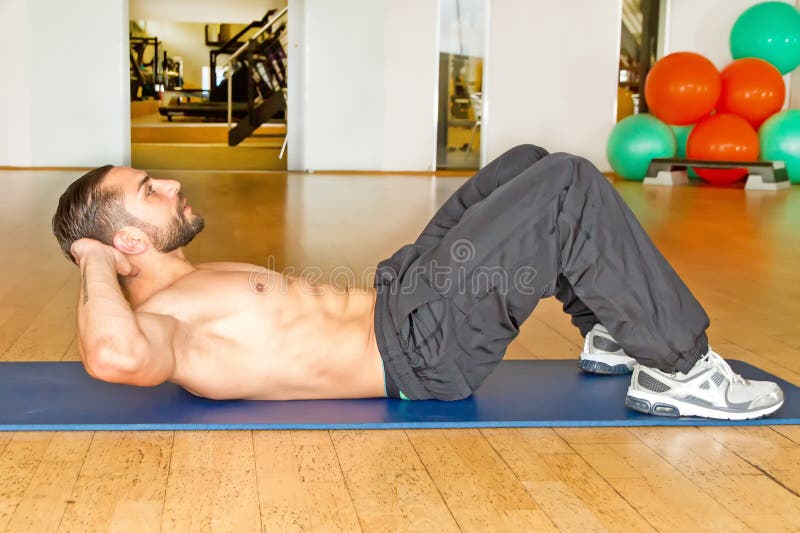 Muskulöser Mann, der Abdominal- Krisen in der Turnhalle tut lizenzfreie stockfotografie Muskulöser Mann, der Abdominal- Krisen in der Turnhalle tut lizenzfreie stockfotografie