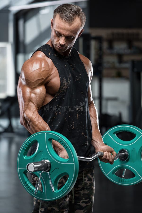 Muskulöser Mann, der in der Turnhalle tut Übungen mit Barbell am Bizeps, starker männlicher Bodybuilder ausarbeitet stockbilder Muskulöser Mann, der in der Turnhalle tut Übungen mit Barbell am Bizeps, starker männlicher Bodybuilder ausarbeitet stockbilder