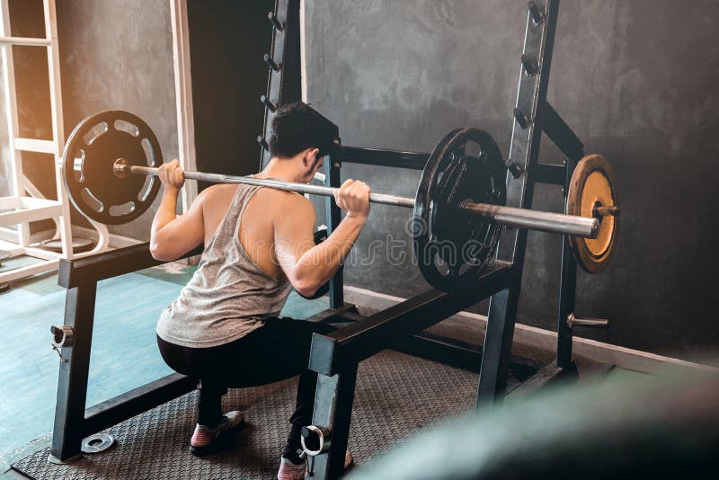 Muskulöser Mann errichtete den Athleten, der in der Turnhalle und im Gewichtheben ausarbeitet lizenzfreies stockbild Muskulöser Mann errichtete den Athleten, der in der Turnhalle und im Gewichtheben ausarbeitet lizenzfreies stockbild