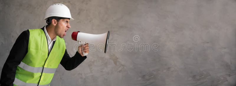 Muslim foreman shouting over grey background. Handsome happy construction worker shouting loud by megaphone with stock image